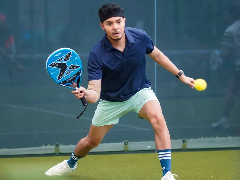 Padelspieler schlägt den Ball auf einem Hallenplatz